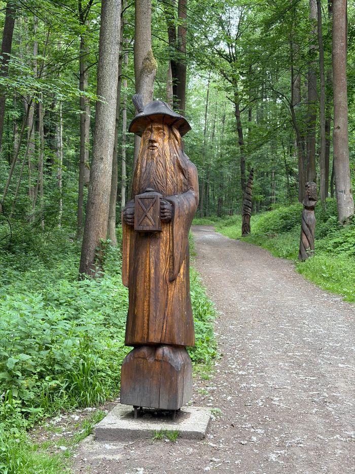 services-03 A carved wooden wizard statue along a forest trail, evoking fantasy themes.